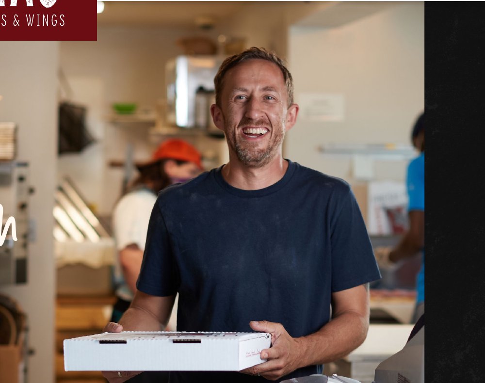 Lena's owner Matt Swank holding a fresh pizza box in the kitchen