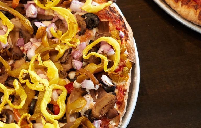 Fresh-baked Lena's pizza loaded with banana peppers, mushrooms, onions, and olives